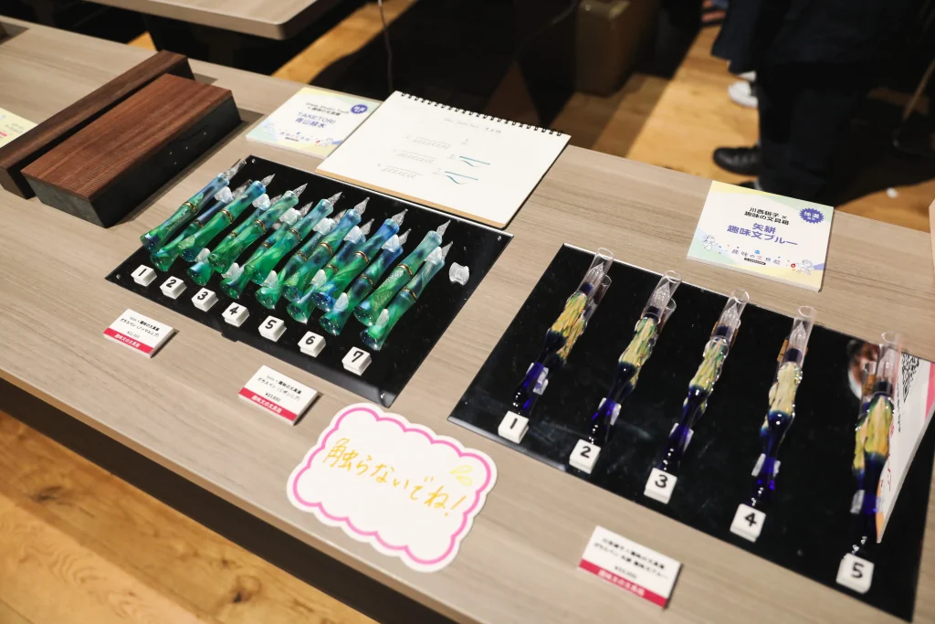 『Glass Studio TooS（グラス スタジオ トゥース）』とのコラボ作品『TAKETORI 青山緑水』（写真1枚目左側）と
『川西硝子』とのコラボ作品『矢絣 趣味文ブルー』（写真1枚目右側）